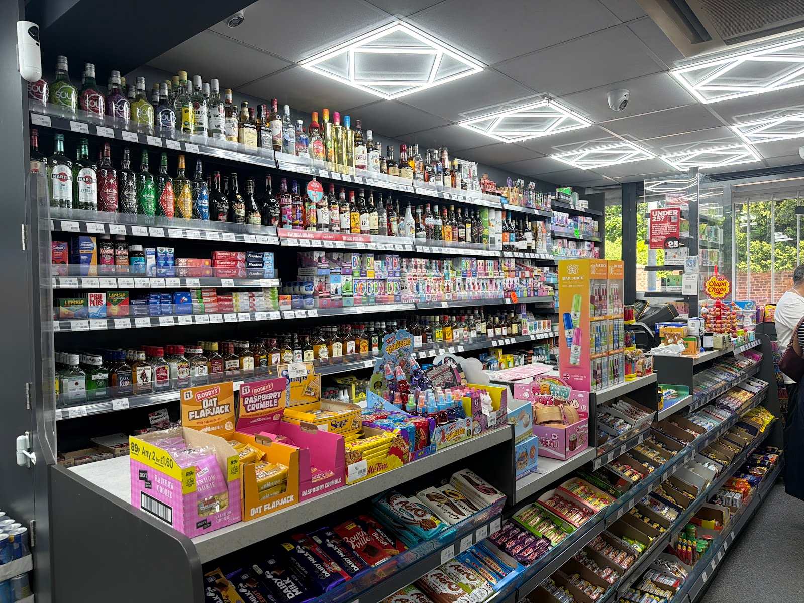 Inside C&K Local Store: shelves stocked with spirits, groceries, snacks and confectionery.